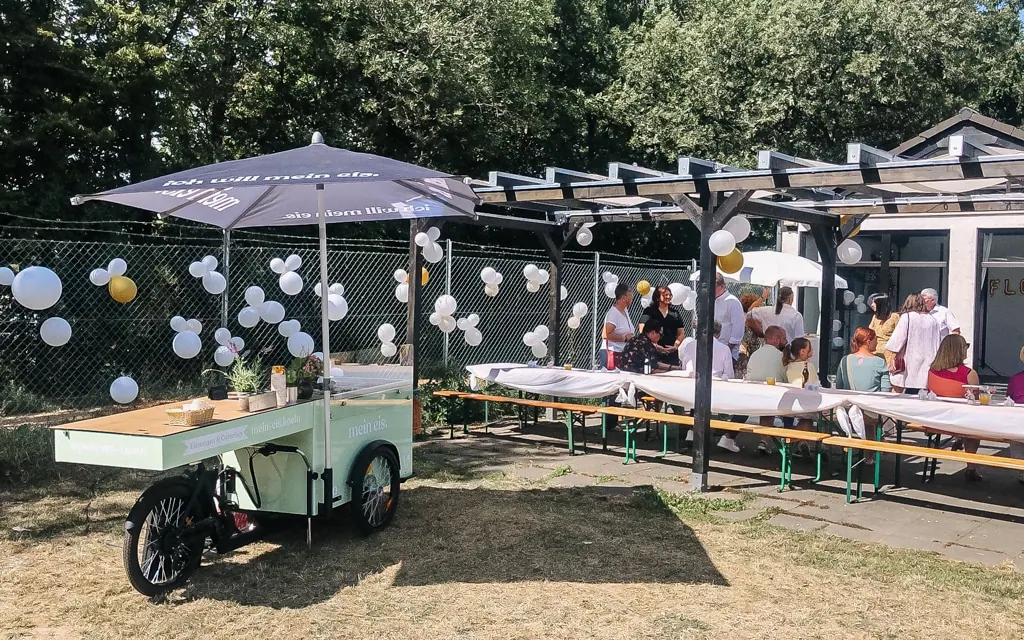 Mintgrünes Eisfahrrad von mein eis mit Schirm bei einer Feier auf einer Terrasse mit Luftballons