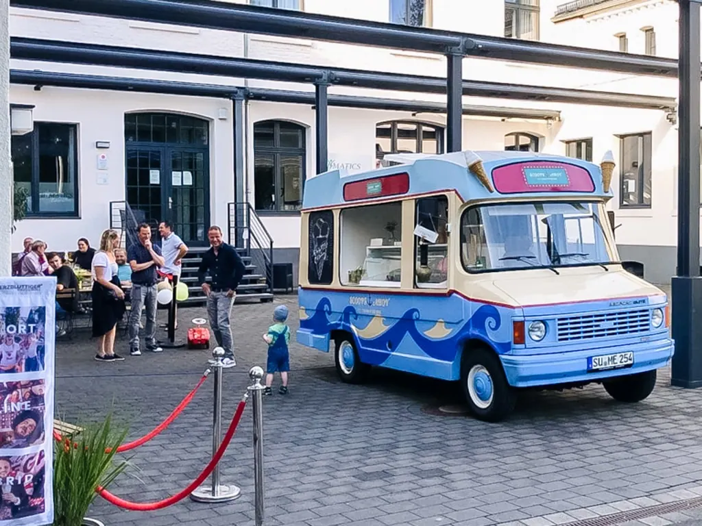 Gäste stehen am Eiswagen von mein eis vor einem Gebäude an