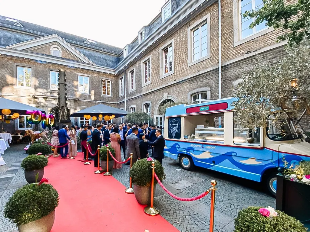 Oldtimer-Eiswagen von mein eis bei einem Empfang mit rotem Teppich im Innenhof eines historischen Gebäudes