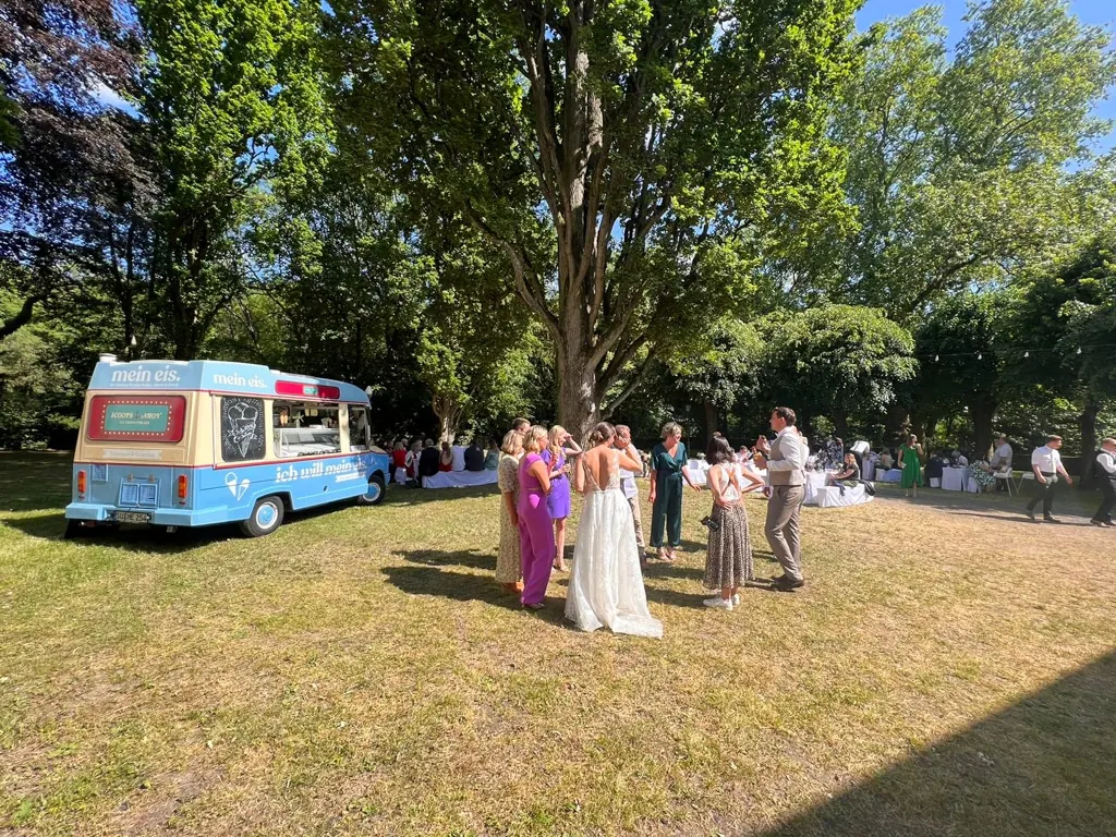 Hochzeitsgäste genießen Eis vom Eiswagen auf einer Wiese