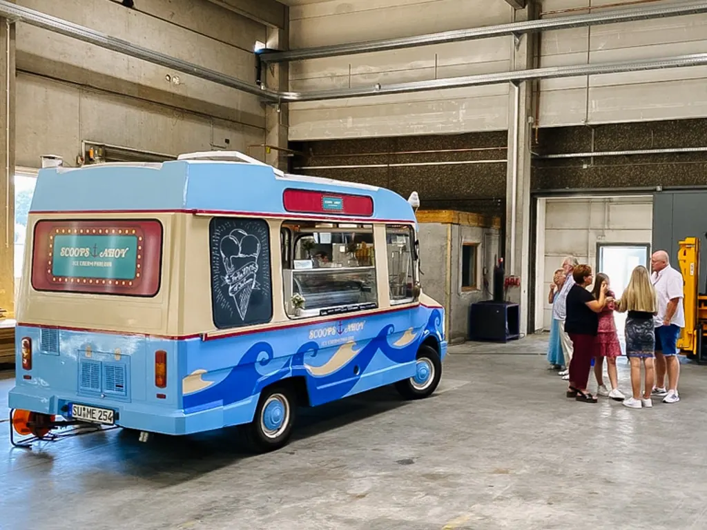 Oldtimer-Eiswagen Kurti von mein eis in einer großen Industriehalle mit Gästen